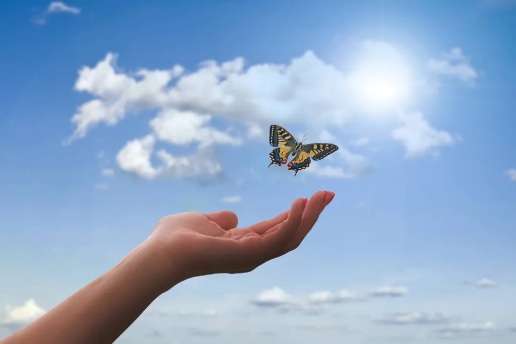 Liberación somato emocional: mano con mariposa con fondo de cielo